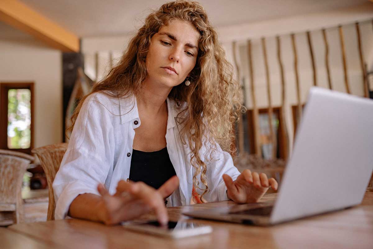 woman at desk working on laptop and smartphone