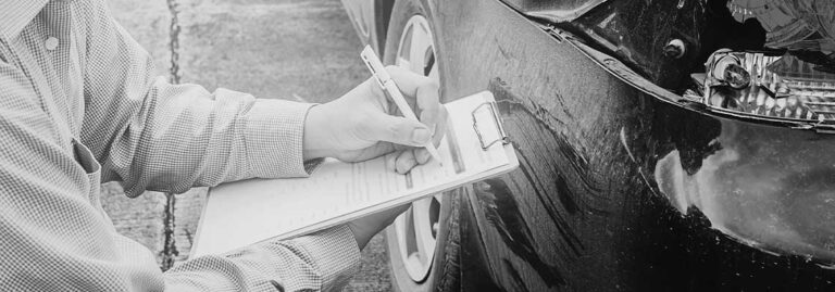 Man in shirt writing on pad looking at car damage