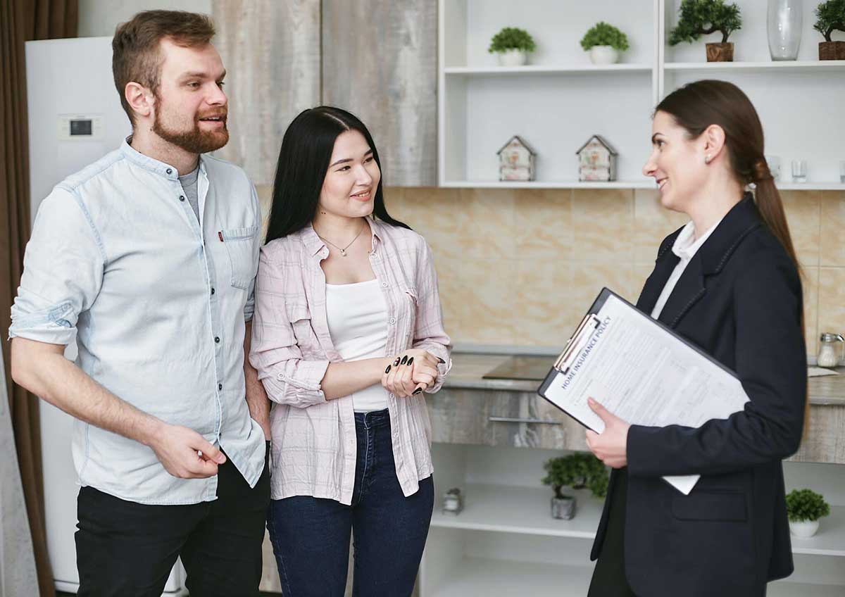 man and woman smiling and talking with woman holding a home insurance policy paper in a pad