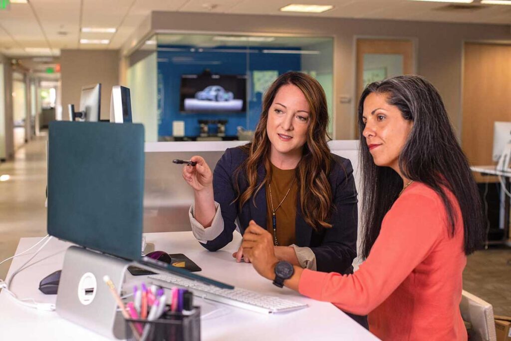 Business women pointing at raised laptop screen