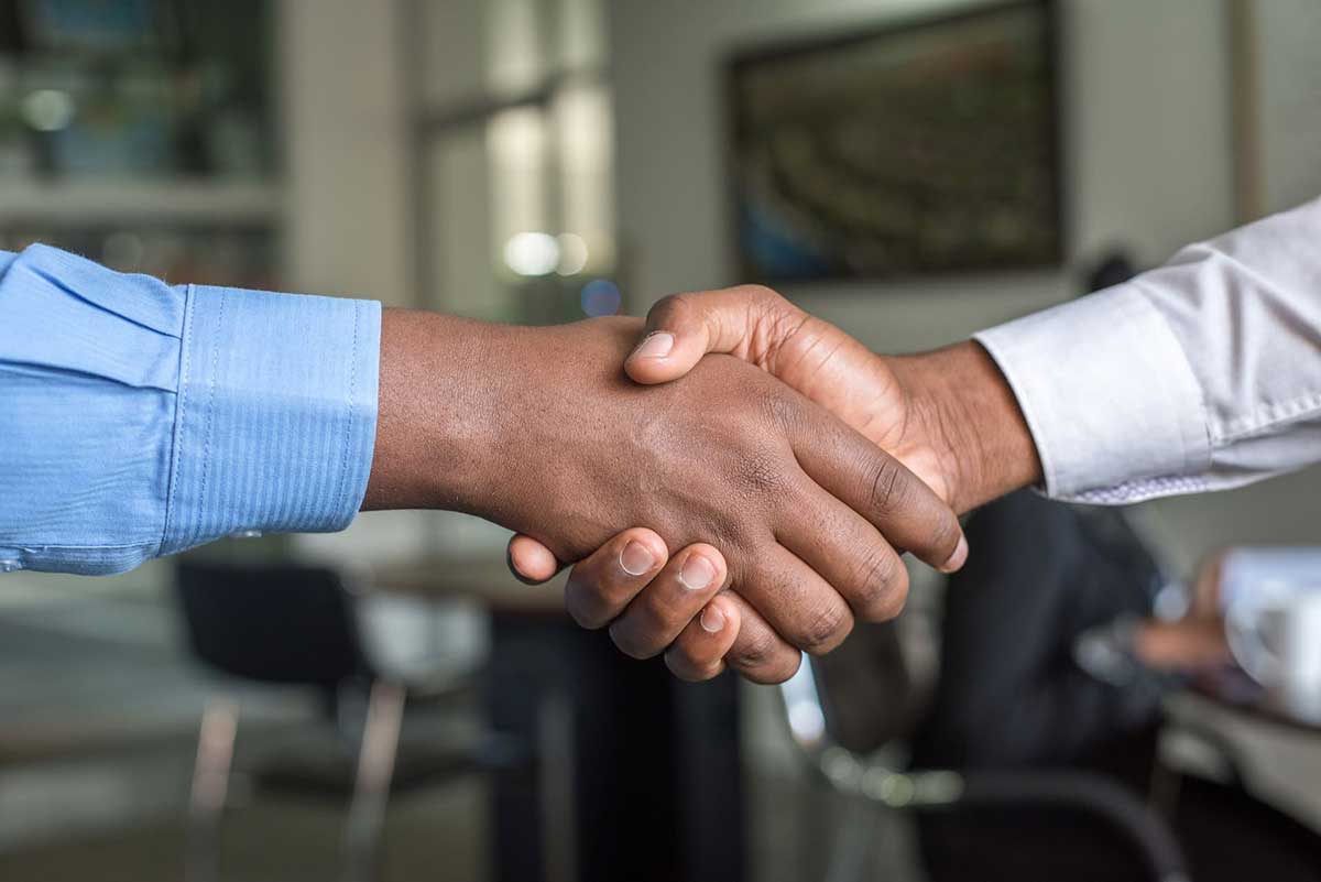 men shaking hands over office background