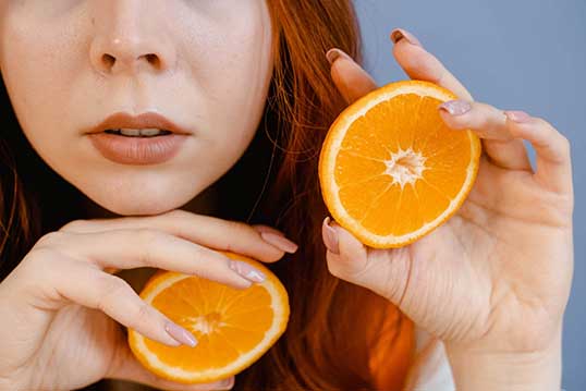 Woman holding 2 halves of orange