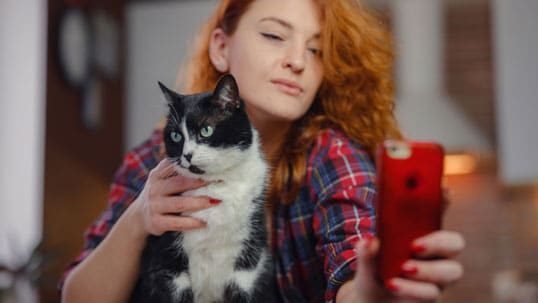 Red hair woman with cat taking a selfie